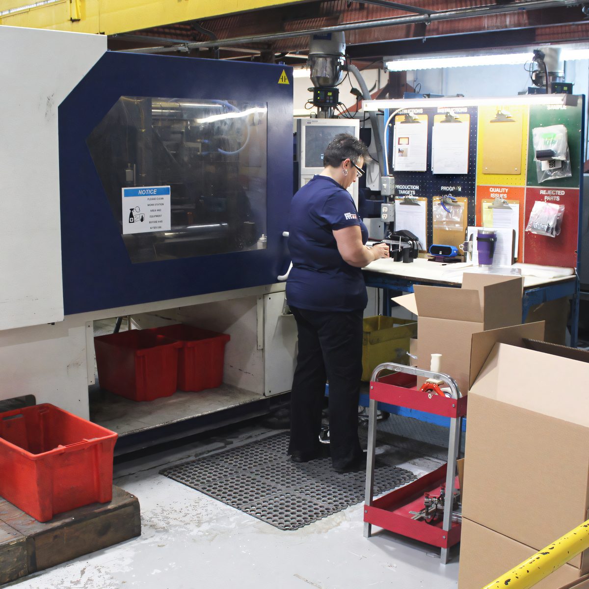 Operator tending a blue injection molding press at Protoplast
